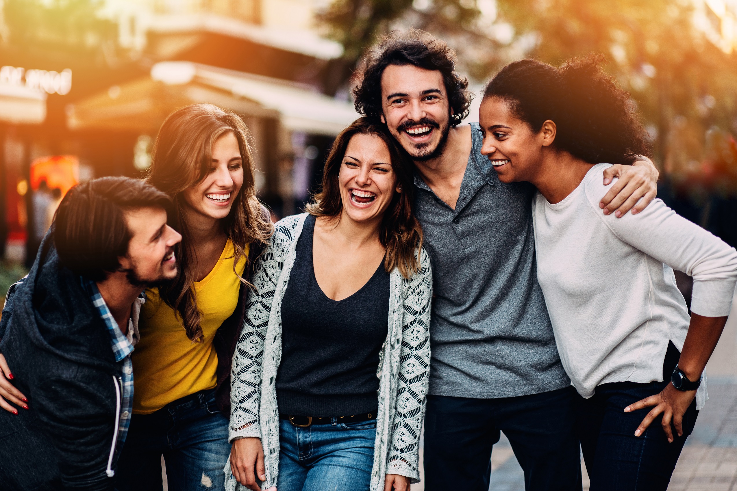 Eine Gruppe aus fünf Personen gehen lachend und eng beieinander durch die Innenstadt.